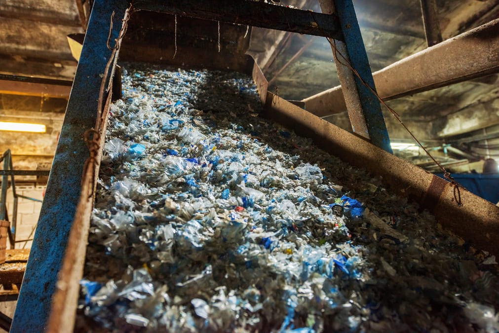 Conveyor belt filled with shredded materials in an industrial facility, showcasing a process for product destruction.