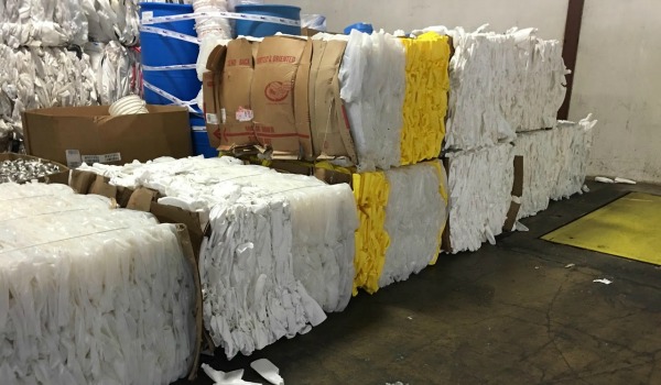 Stacked bales of sorted plastics in a warehouse, ready for industrial plastics recycling