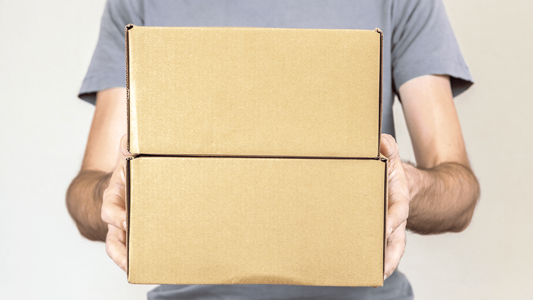 A man carries two cardboard boxes to show how to recycle cardboard