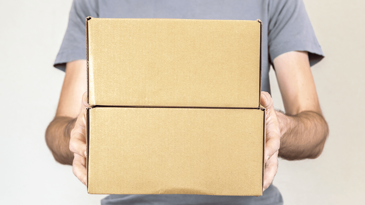 A man carries two cardboard boxes to show how to recycle cardboard