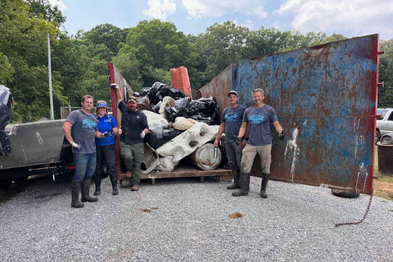 Volunteers posing in front of trash removed from the Tennessee River